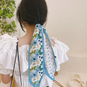 Élégant foulard en soie à fleurs bleues porté en bandeau avec haut blanc