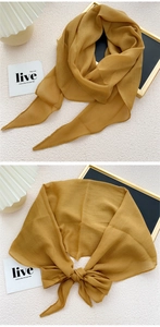 Detail of mustard yellow chiffon scarf showing smooth hemmed edges and lightweight drape
