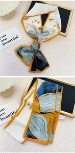 Détail d'un foulard étroit en soie blanc et bleu avec motif oiseaux et bordure orange