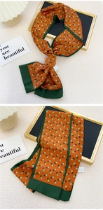 Détail d'un foulard en soie orange à fleurs avec bords verts et texture fluide soyeuse