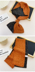 Détail d'un foulard en soie double face avec motifs floraux orange et vagues noires
