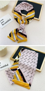 Détail d'un foulard étroit en soie montrant le motif mors et un nœud élégant