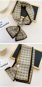 Détail d'un foulard en soie champagne avec imprimés nœuds noirs et texture satinée