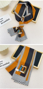 Détail d'un foulard étroit avec motifs géométriques orange et noirs et texture soyeuse