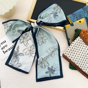 Foulard étroit en soie élégant avec imprimés floraux noué en nœud sur fond luxueux