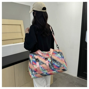 Detail view of large travel bag featuring colorful polka dots and pink straps on a model