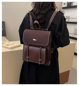 Close-up of vintage dark brown PU leather backpack with contrast stitching and metal buckles