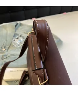 Close-up of brown PU leather bag handle with white stitching and brass metal hardware