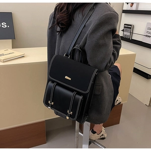 Model wearing a vintage black PU leather backpack with gold metal plate and white stitching
