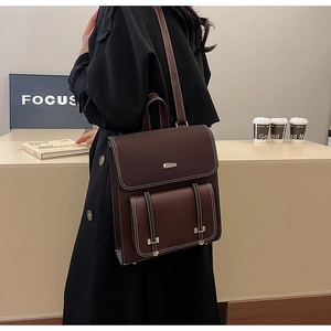 Brown vintage PU leather backpack with buckle straps worn by a model in a minimalist setting