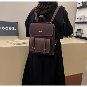 Rear view of vintage dark brown PU leather backpack with gold metal buckles on a model