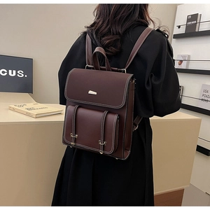 Detail of dark brown vintage PU leather backpack with contrast stitching and gold buckles