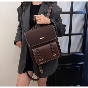Detail view of a vintage dark brown PU leather backpack with decorative metal buckles
