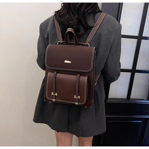 Detail of dark brown vintage PU leather backpack with contrast stitching and gold buckle