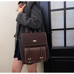 Detailed view of dark brown PU leather backpack with vintage white stitching and gold hardware