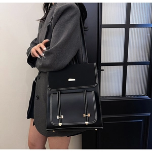 Detail of black PU leather backpack featuring white contrast stitching and gold metal buckle