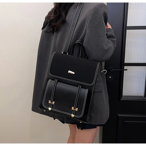 Detail view of black PU leather backpack with contrast stitching and gold metal buckle
