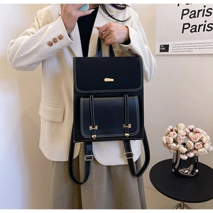 Detail of black PU leather backpack featuring white contrast stitching and gold metal trim
