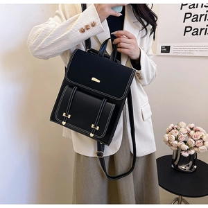 Detail of structured black PU leather backpack featuring white stitching and gold hardware