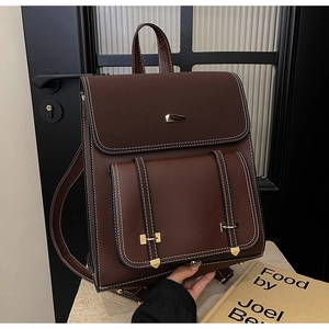 Detail of dark brown vintage PU leather backpack with contrast stitching and metal buckle
