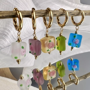 Five pairs of vintage stainless steel hoop earrings with colorful floral glass charms