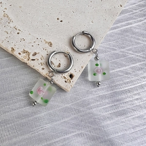 Detail of square frosted glass pendant earring with pink rose and silver metal hoop