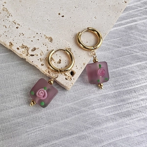 Detail of vintage gold hoop earrings with square purple glaze and rose pendant decoration