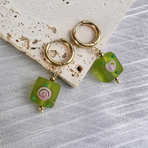 Detail of square green glass earring charms with pink rose patterns and gold hoops