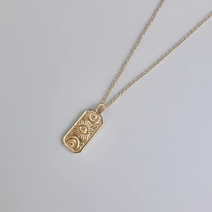 Detailed relief of sun moon star and evil eye on gold rectangular pendant necklace