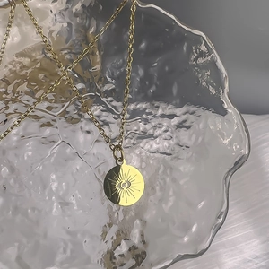 Detailed close-up of 18K gold-plated hollow evil eye pendant on a glass display