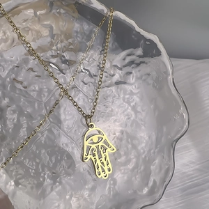 Detailed macro view of 18K gold plated Hamsa hand pendant with cutout evil eye detail