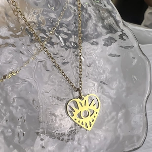 Macro view of a 18K gold-plated hollow heart evil eye pendant necklace on glass