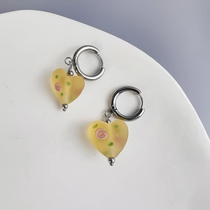 Macro detail of yellow frosted heart earrings featuring pink floral resin patterns
