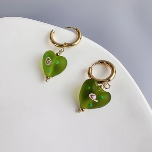 Close-up of green frosted glass heart earrings with rose hand-painted texture