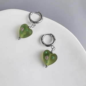 Detail of green frosted heart earrings with pink floral patterns on a white plate