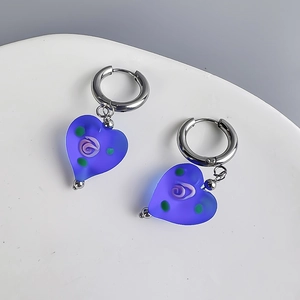 Macro detail of frosted blue glass heart earring with purple spiral texture and silver hoop