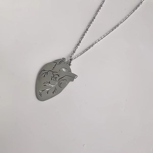 Gros plan du pendentif cœur anatomique argenté avec détails de texture évidés