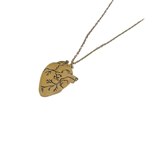 Collier minimaliste en acier inoxydable doré avec pendentif cœur anatomique sur fond blanc