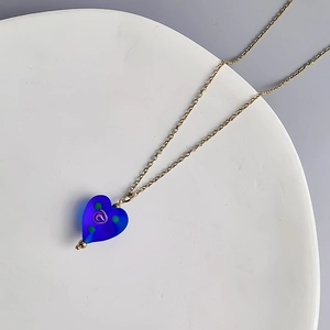 Gros plan sur le pendentif coeur bleu à motif spirale sur chaîne en acier doré
