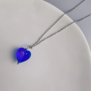 Vue détaillée du collier pendentif cœur en verre dépoli bleu avec motif en spirale blanc