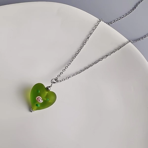 Détail du pendentif coeur en verre vert avec motifs floraux sur une fine chaîne argentée
