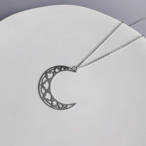 Détail du pendentif croissant de lune évidé sur une chaîne en acier inoxydable argenté