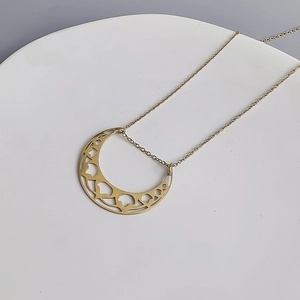 Détail macro d'un pendentif lune creux doré avec des motifs internes complexes