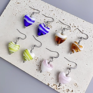 Sweet heart-shaped ink ripple glass earrings in four vibrant colors displayed on stone
