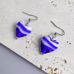 Macro detail of heart-shaped blue and white striped resin earrings with silver hooks