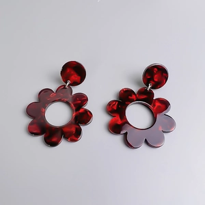 Dettaglio di orecchini a fiore in acrilico rosso scuro con trama marmorizzata e design rétro