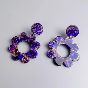 Dettaglio orecchini floreali in acrilico con trama pittura a olio viola e blu stellato
