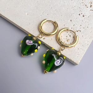 Vue macro de boucles d'oreilles cœur en verre vert faites main sur un socle en pierre