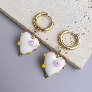 Vue détaillée de boucles d'oreilles en verre en forme de cœur avec anneaux en acier doré