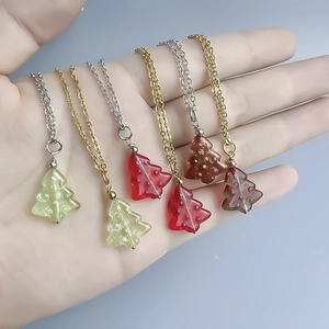 Handheld showcase of colorful glass Christmas tree pendants on gold and silver chains